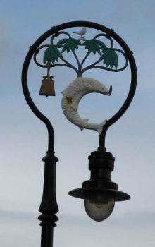 Straenlaterne mit den Symbolen aus dem Stadtwappen von Glasgow: Vogel, Fisch mit Ring im Maul, Baum und Glocke